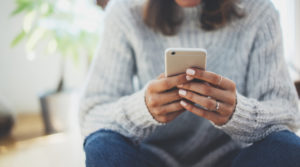 Woman displays importance of mobile first design by browsing the web on her phone